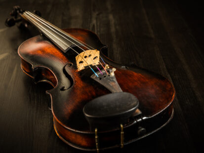 Old violin in vintage style on wood background